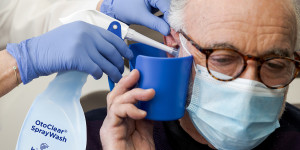 Patient receiving ear irrigation from clinician.
